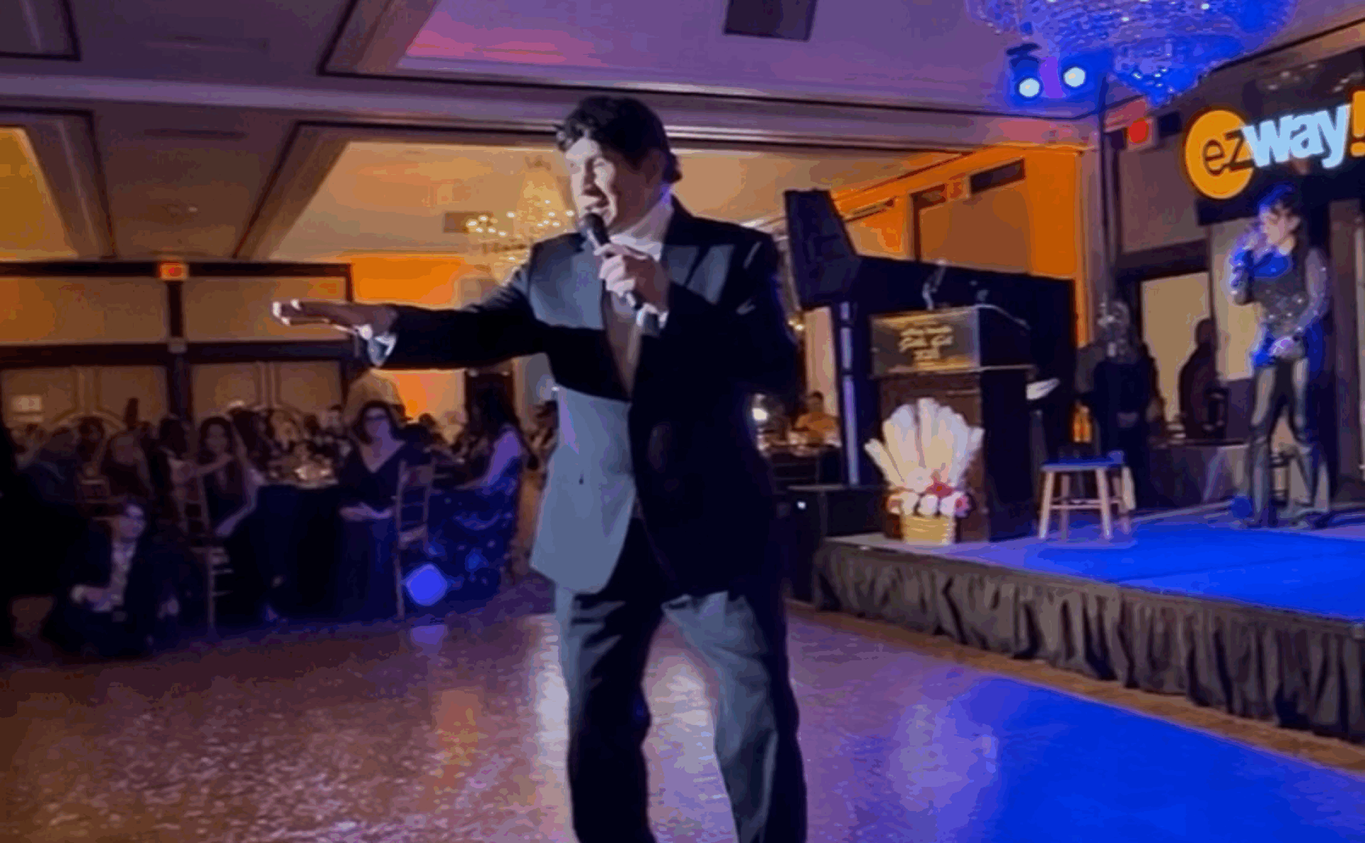 John Michael Ferrari singing live on stage in a suit